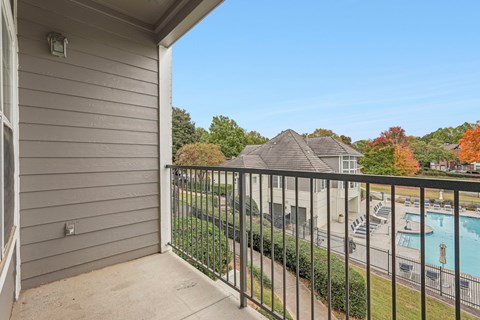 A balcony overlooks a pool and a residential area.