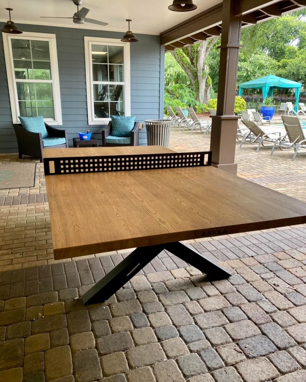 a picnic table on a porch with a house in the background