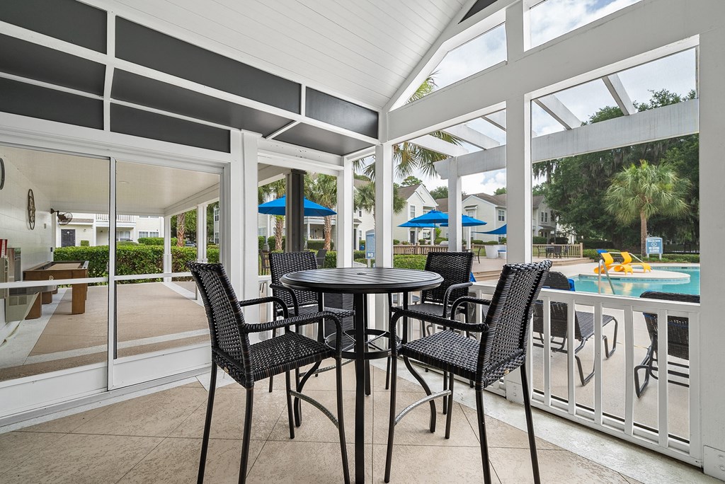 a patio with a table and chairs next to a pool