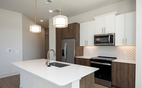 A modern kitchen with a white countertop and stainless steel appliances.