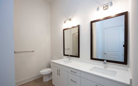 A white bathroom with a toilet, sink, and mirrors.
