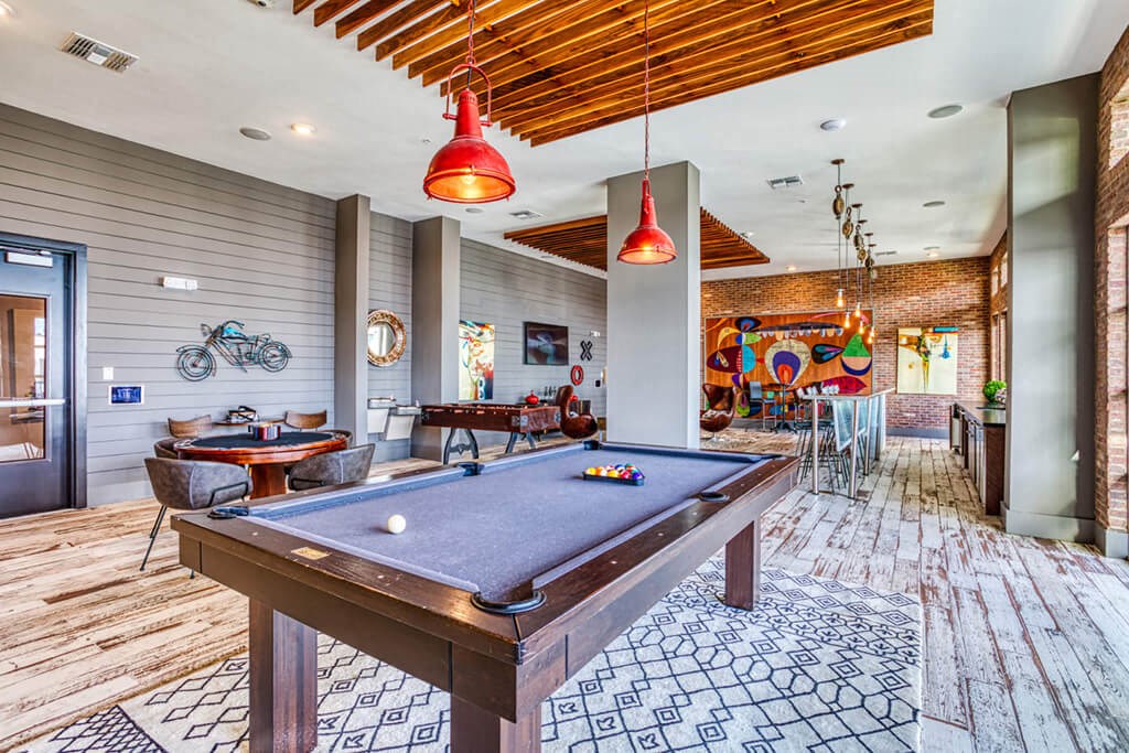 2-Bedroom Apartments in Maitland, FL - The Parker at Maitland Station - Clubhouse with a Mini Kitchen, Table with Chairs, Billiards Table, and Foosball Table.