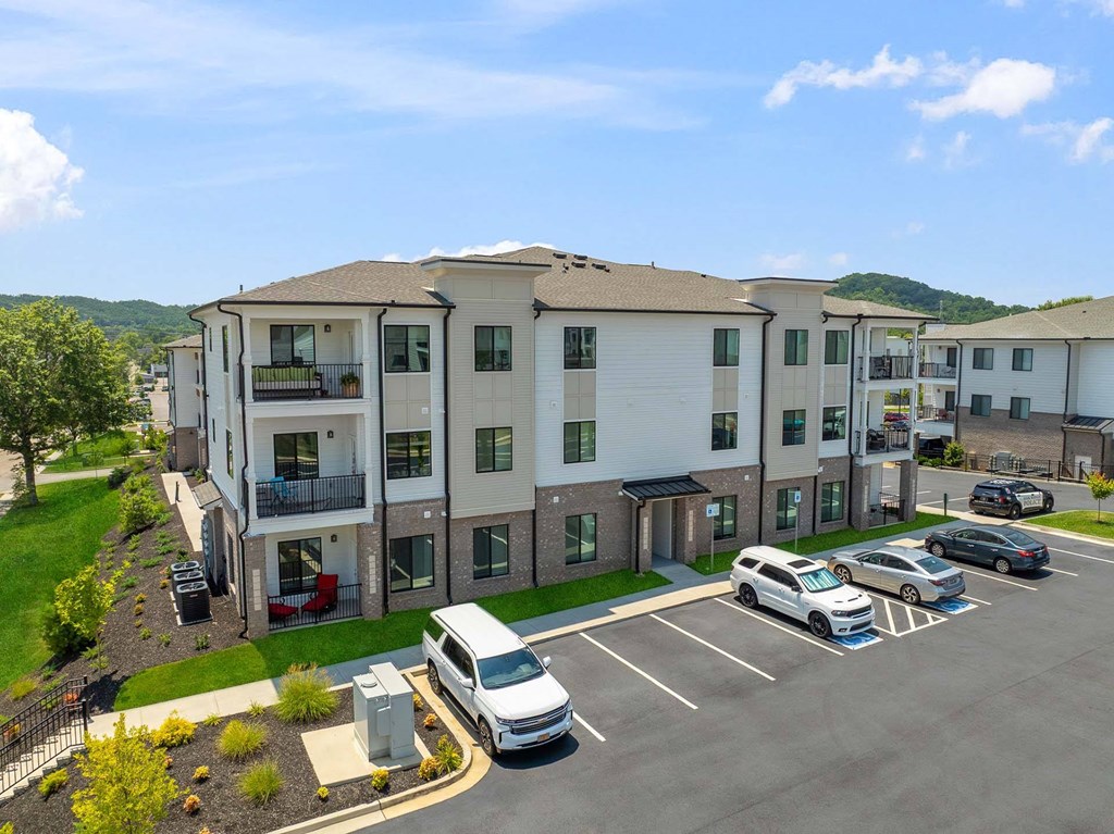 A parking lot with a white van and a black car in front of a building.