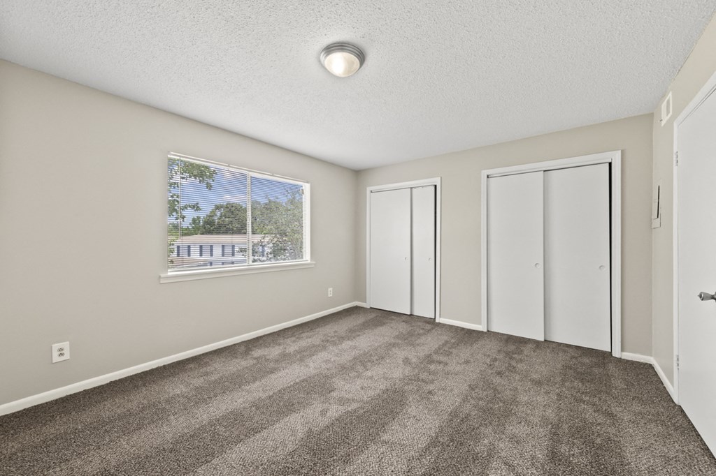 an empty living room with carpet and a window