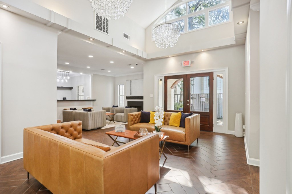 A living room with a brown couch and a chandelier.