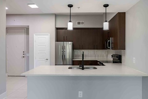 A modern kitchen with a white countertop and stainless steel appliances.