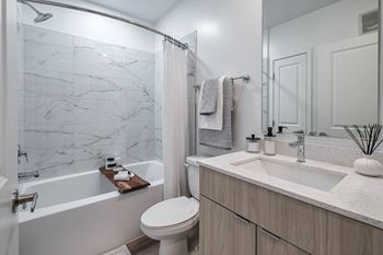 A white toilet sits next to a marble-tiled shower in a modern bathroom