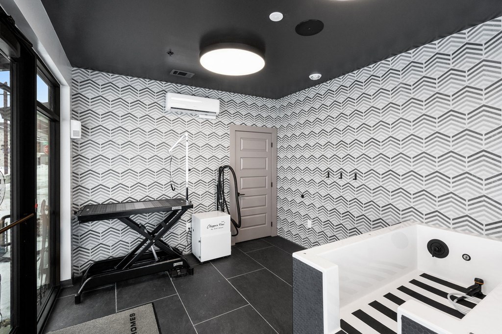 A bathroom with a white tub and a black and white tiled wall.