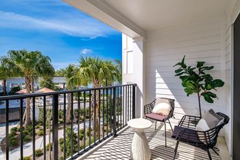 a balcony with two chairs and a table and a view of the water at Altis Twin Lakes Apartments, Kissimmee, FL 34744