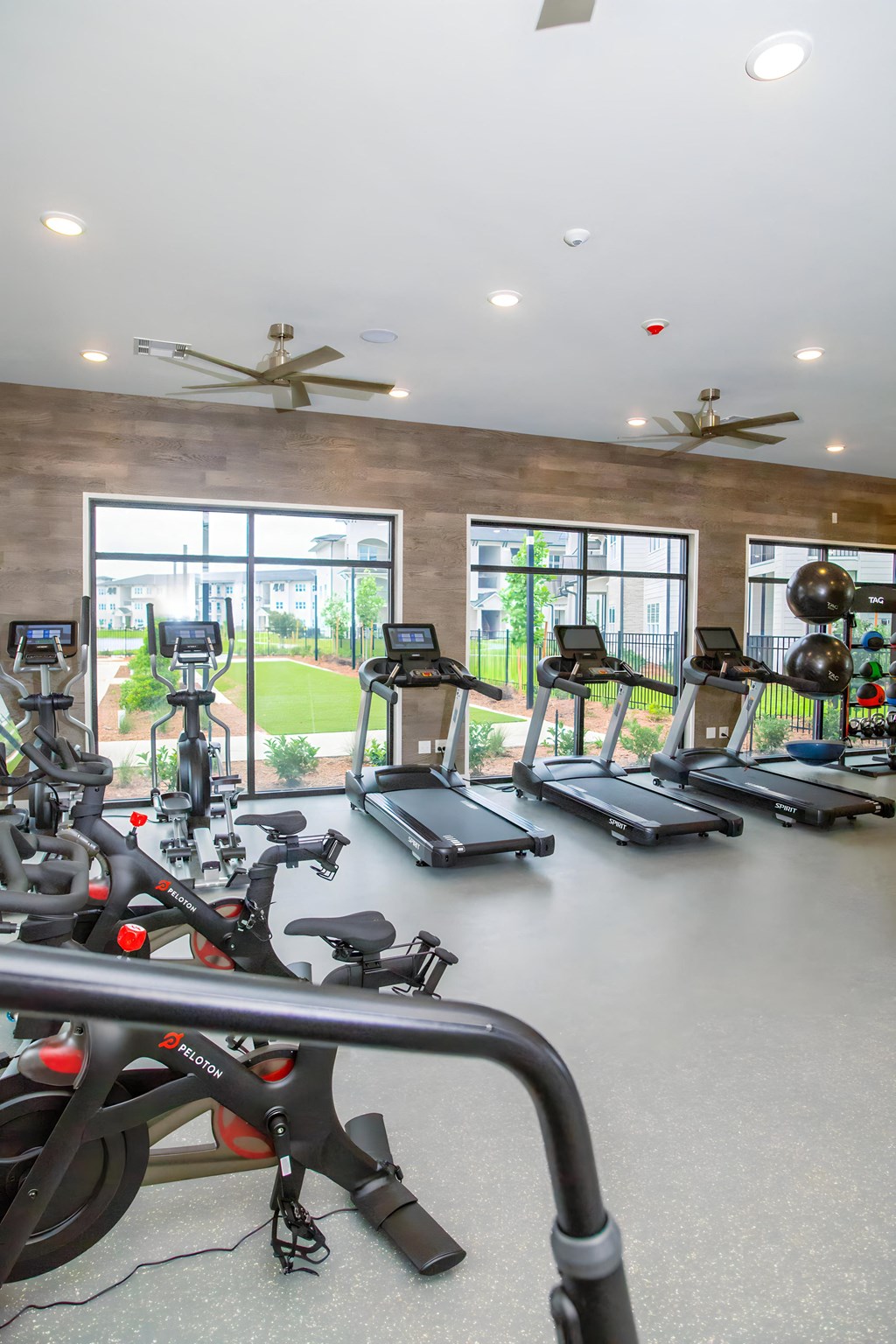 a gym with cardio equipment and windows in a building