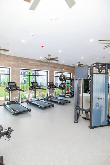 a gym with cardio equipment and windows in a building