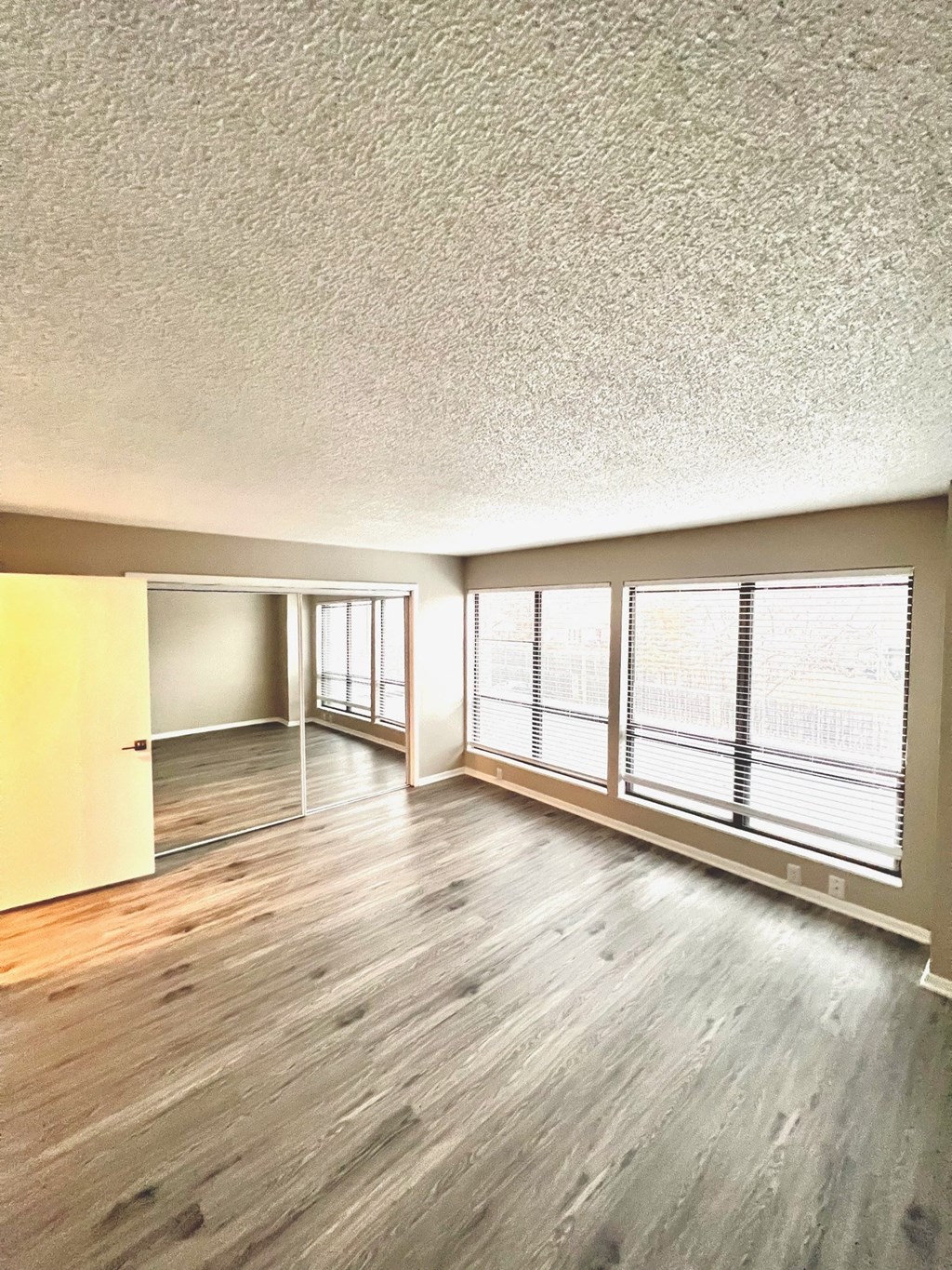an empty living room with wood floors and a large window