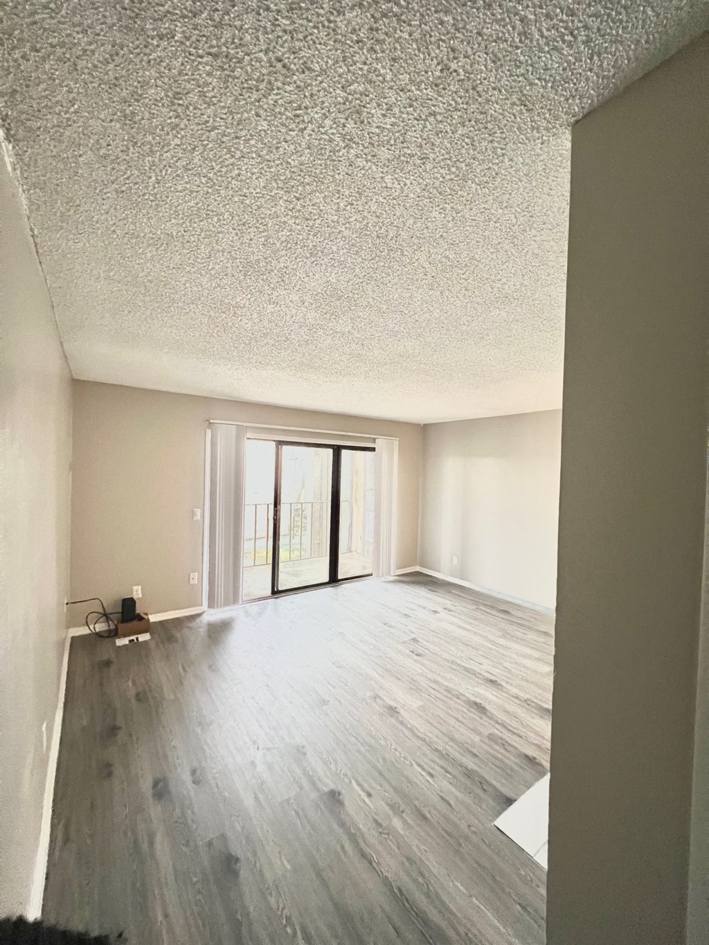 an empty living room with wood floors and a sliding glass door