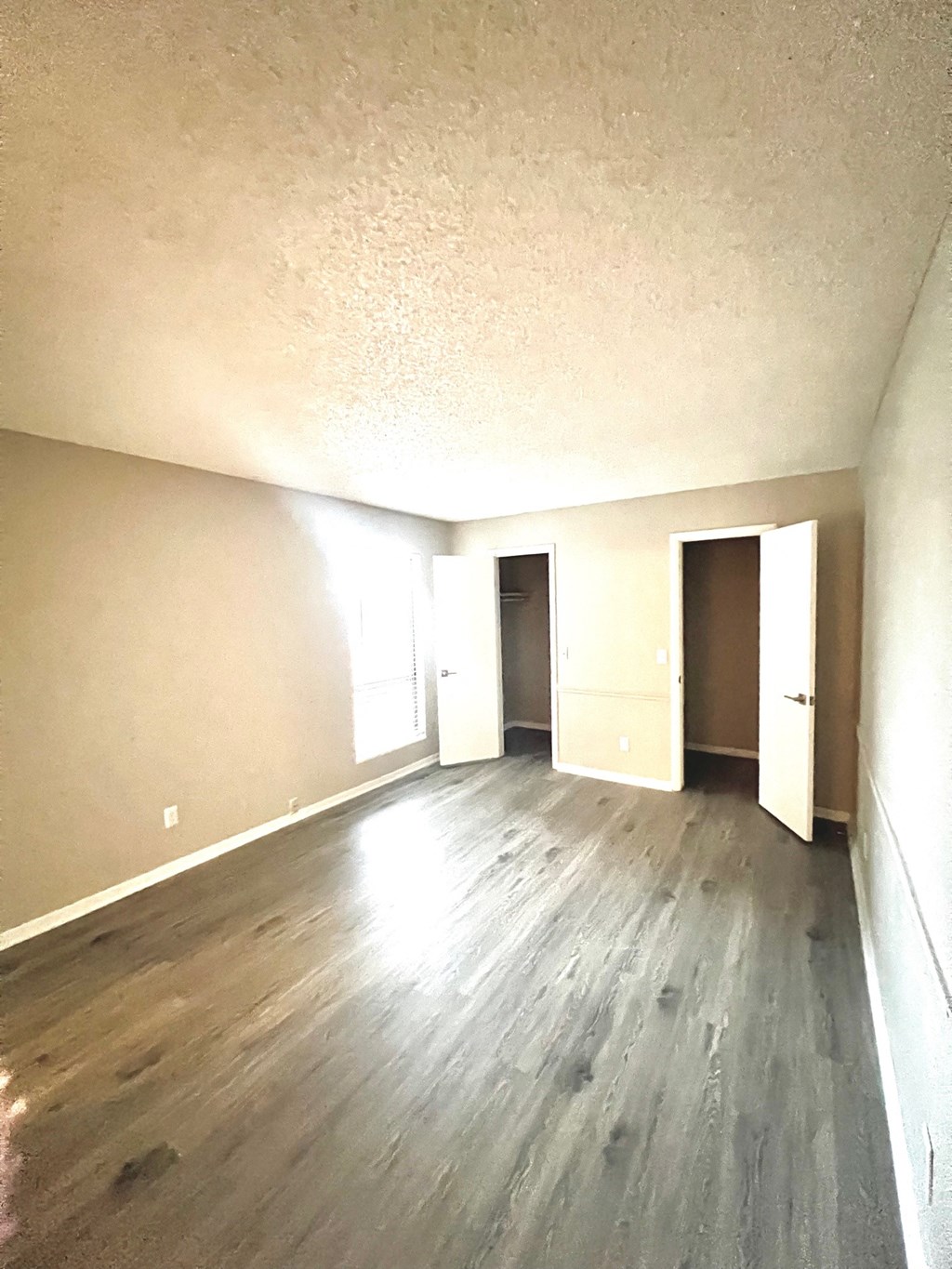 an empty living room with wood floors and white walls