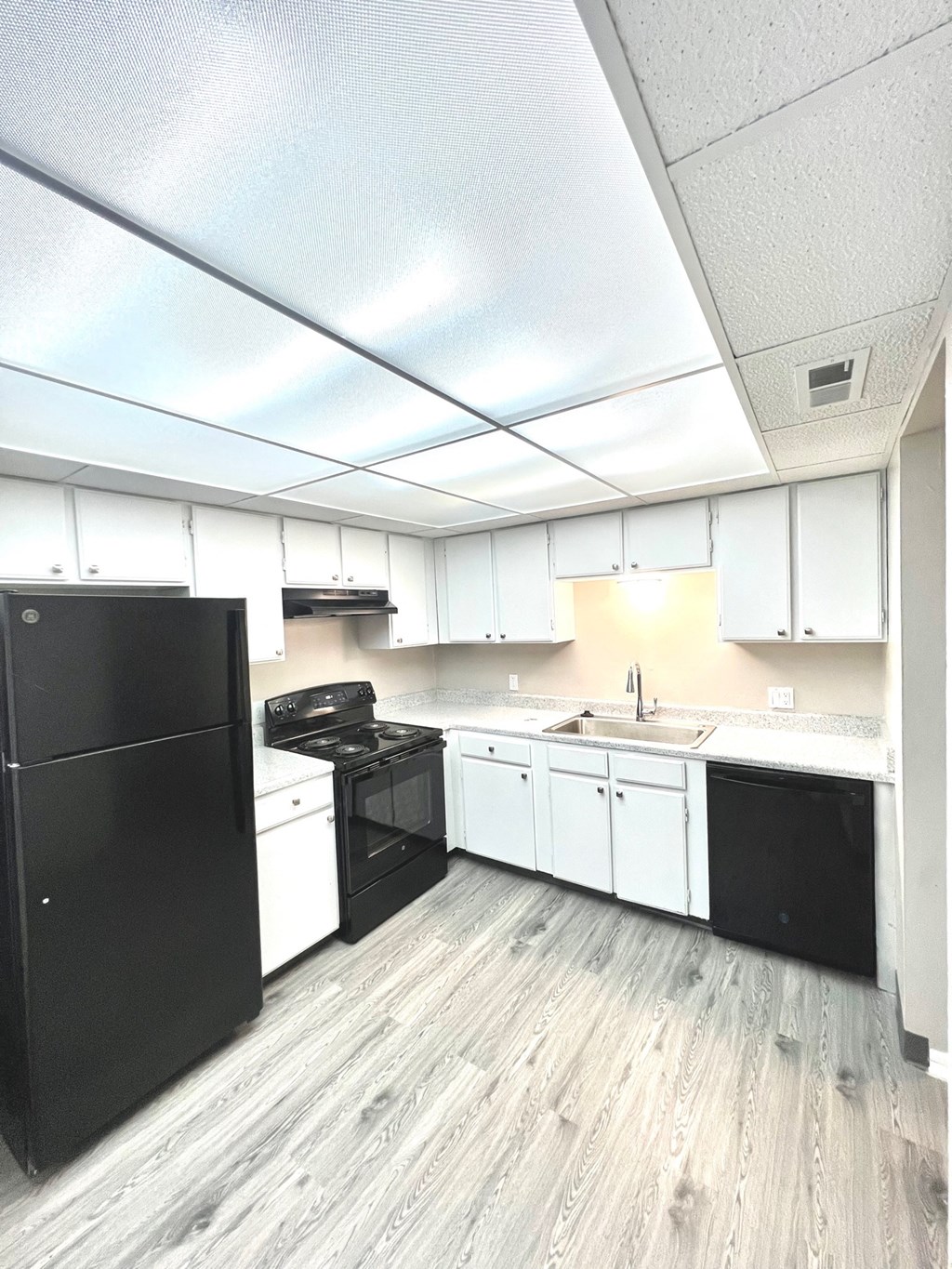 an empty kitchen with white cabinets and black appliances