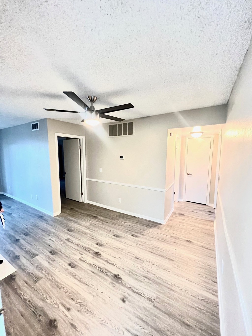 an empty living room with wood floors and a ceiling fan