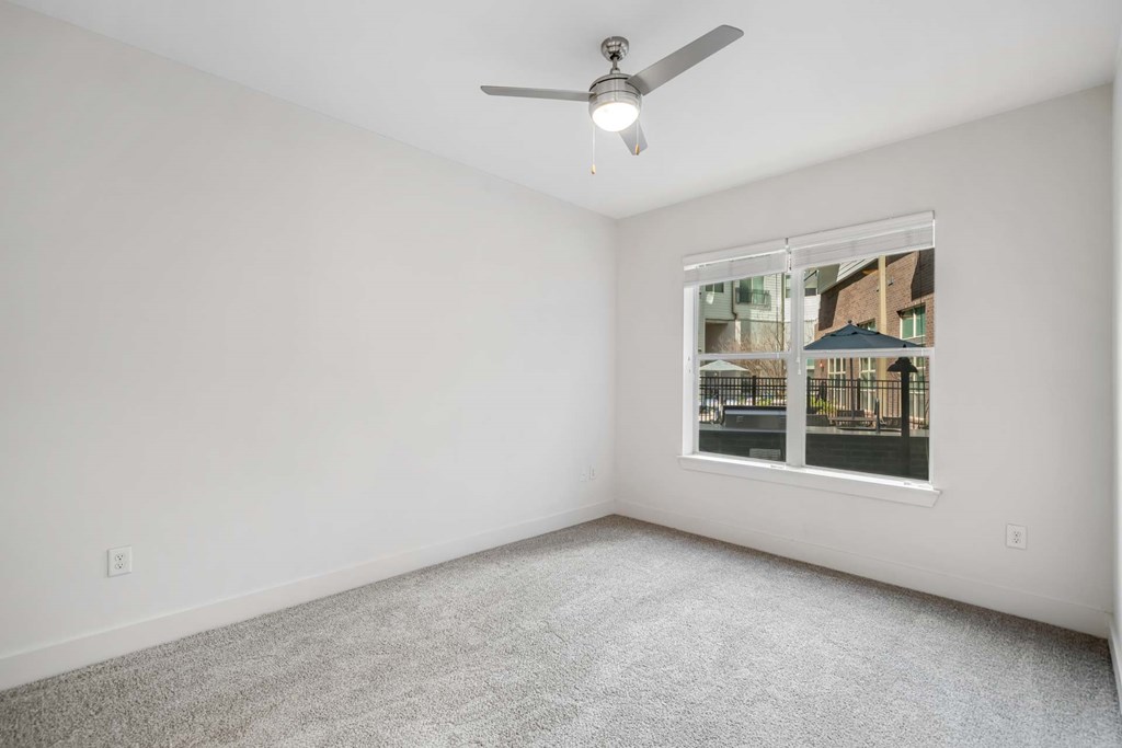 A room with a ceiling fan and a window showing an outdoor view.