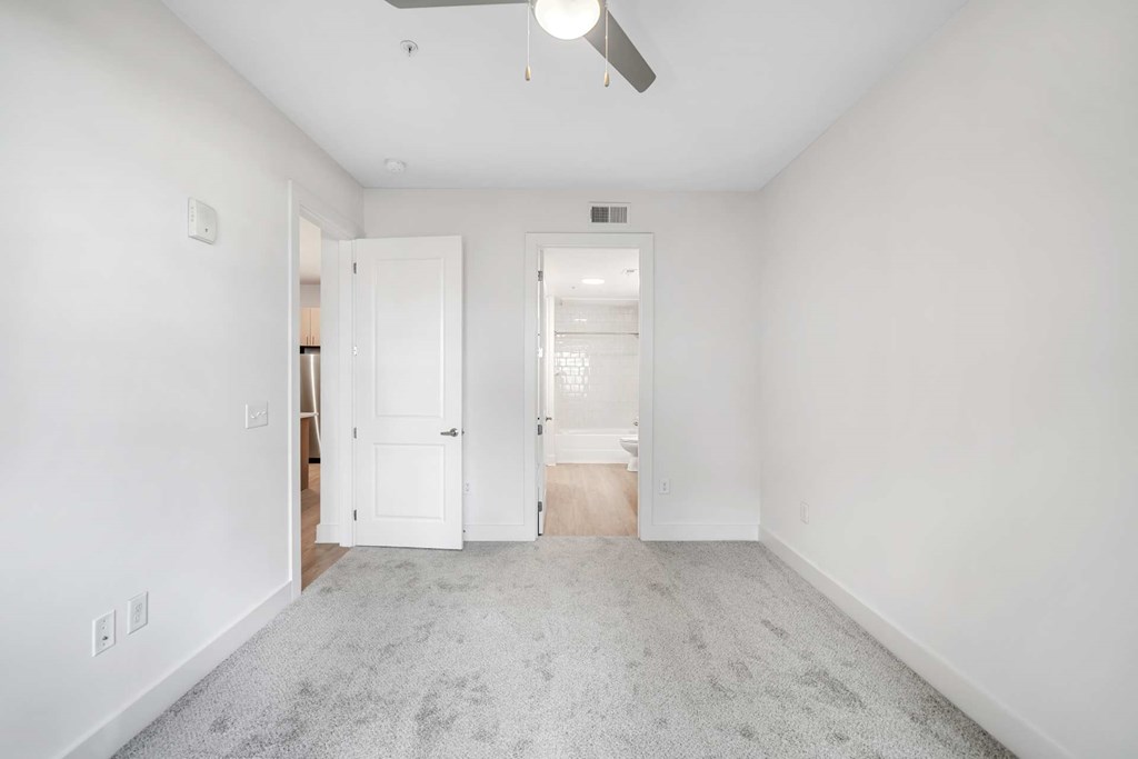 A spacious room with a ceiling fan and carpeted floor.