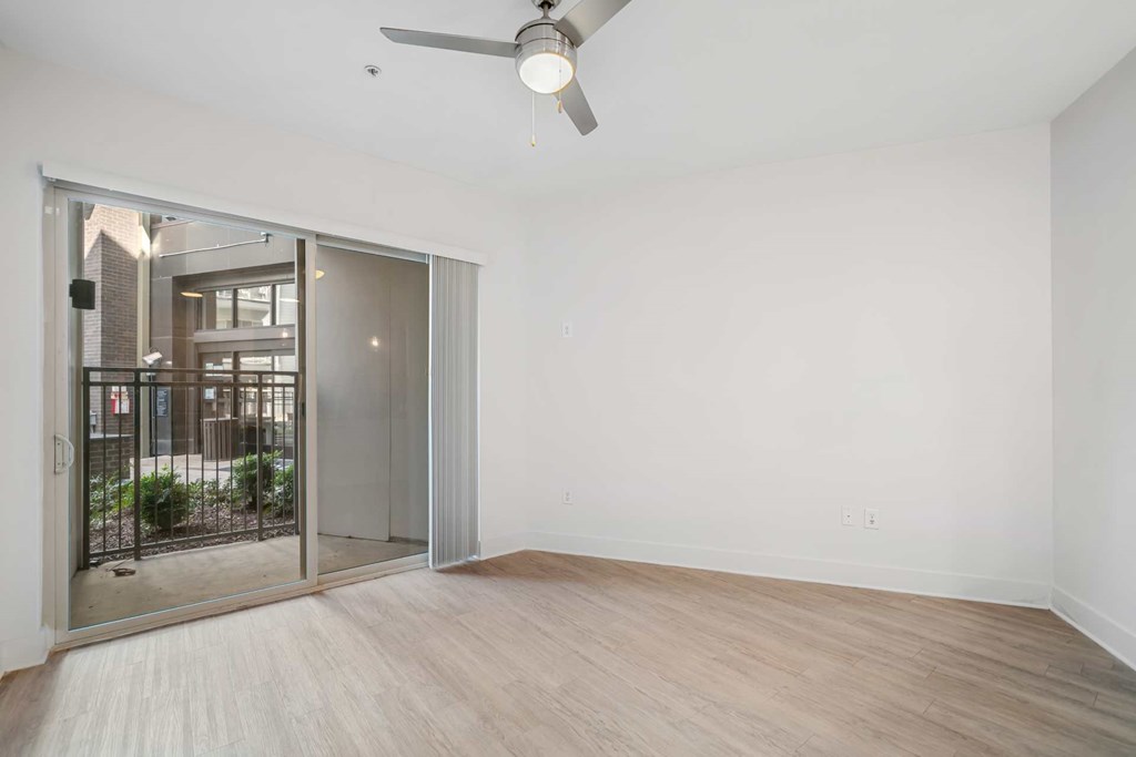 A room with a sliding glass door leading to a balcony.