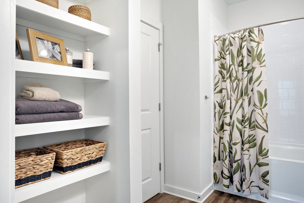a bathroom with white shelves and a shower curtain with a green and white tree print