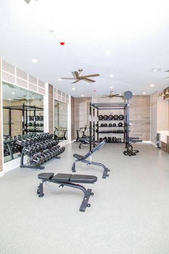 a workout room with weights and a ceiling fan