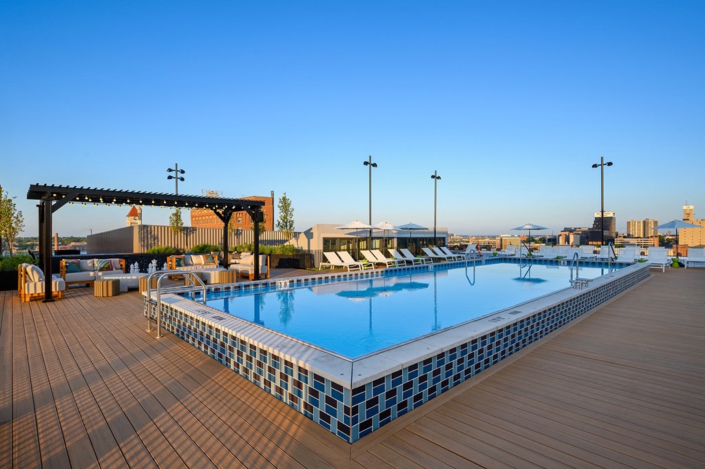 a pool on the rooftop of a hotel with a clear blue sky in the background