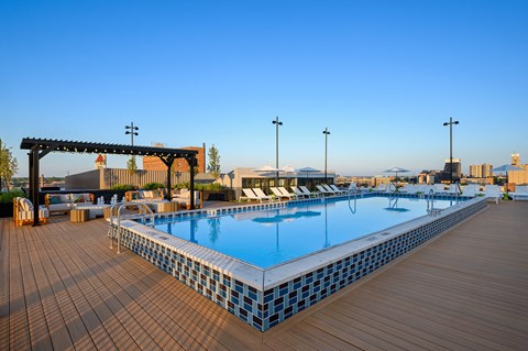 a pool on the rooftop of a hotel with a clear blue sky in the background