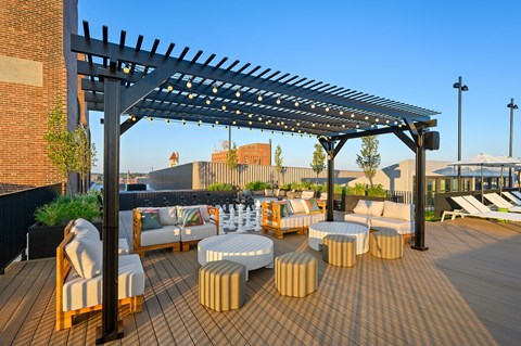 a roof deck with couches and tables and a pergola