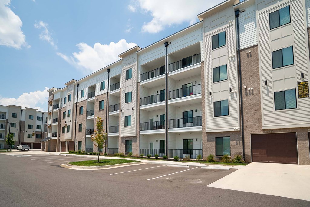 Apartment building with a parking lot in front.