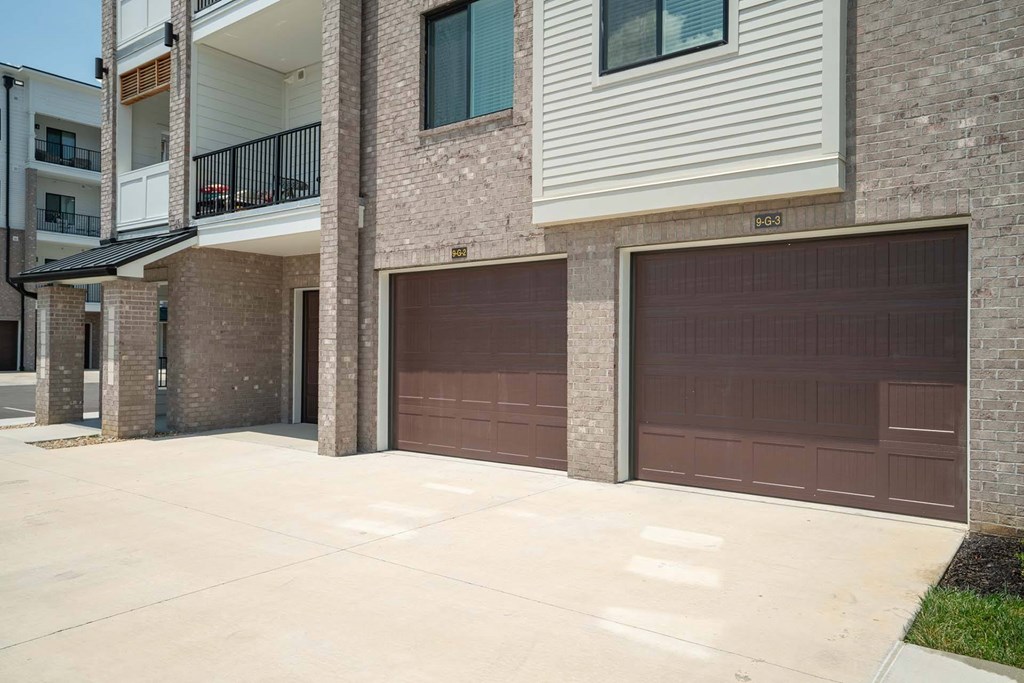 A building with brown garage doors and a balcony.