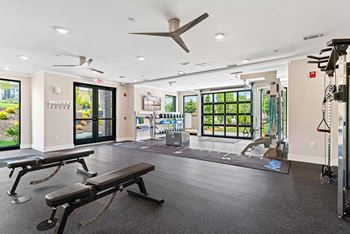 A gym with a bench, weights, and a fan.