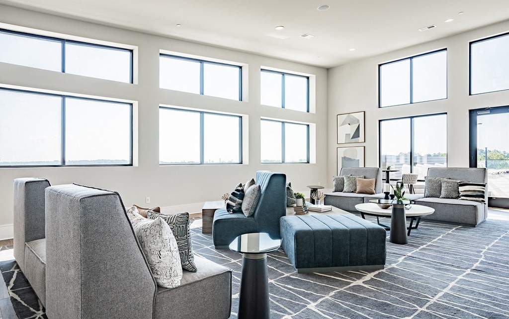 a living room with couches and chairs and large windows