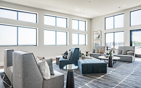 a living room with couches and chairs and large windows