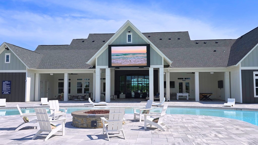 A poolside area with chairs and a building in the background.