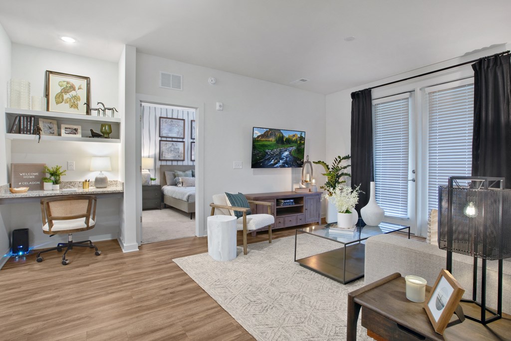 a spacious living room with a desk and chair and a flat screen tv on the wall