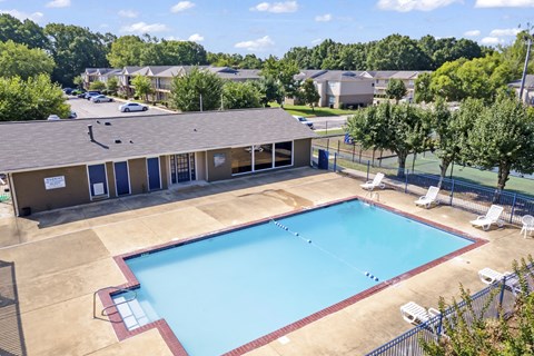 an aerial view of a swimming pool with a building and trees