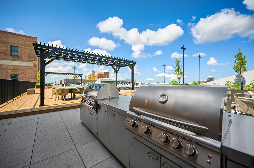 an outdoor patio with a grill and a pergola with a blue sky in the background