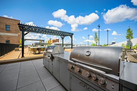 an outdoor patio with a grill and a pergola with a blue sky in the background