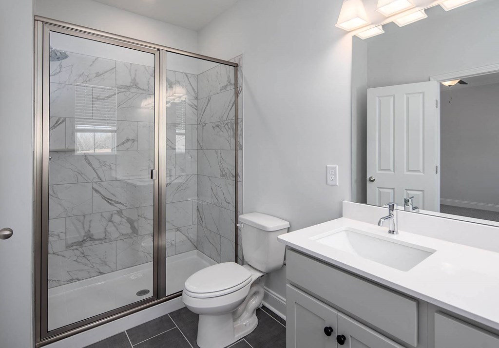 a bathroom with a white sink and toilet next to a shower with a glass door