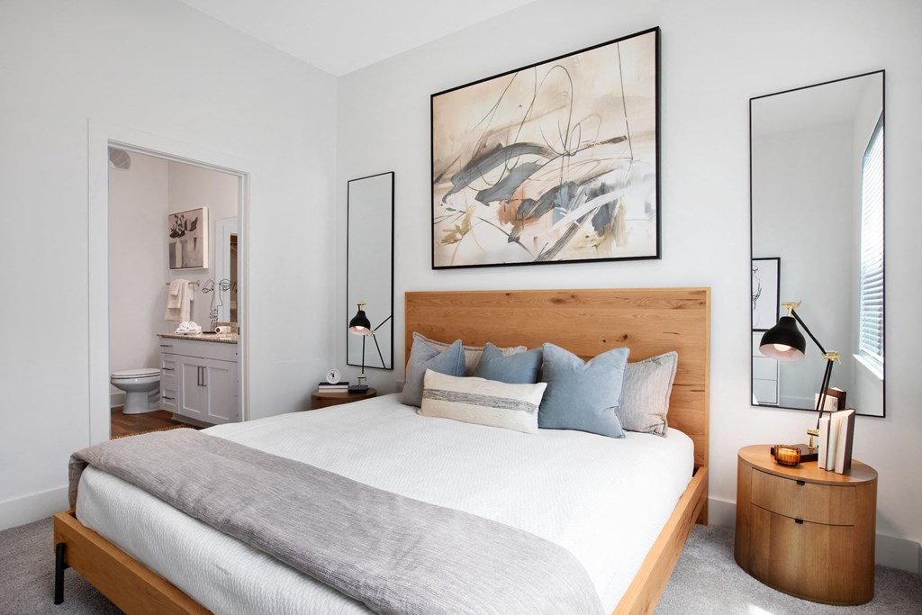 Pet-Friendly Apartments in Norcross, GA - The Darnell - Bedroom with Bed, Nightstands, Lamps, Wall Decor, and Attached Bathroom