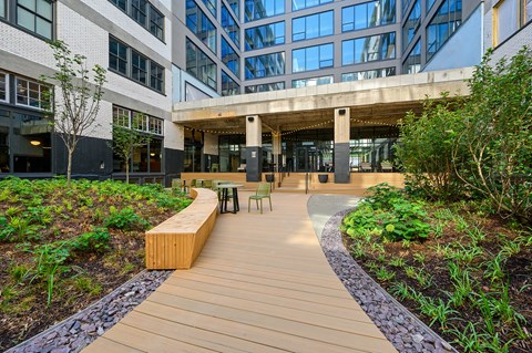 a wooden walkway with benches and chairs in front of a building