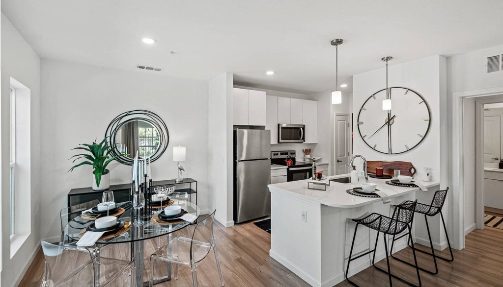 an open kitchen and dining room with a large clock on the wall