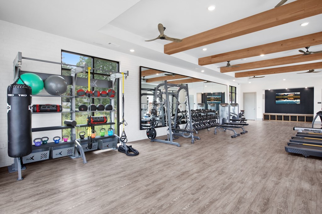 a spacious fitness room with hardwood floors and white walls