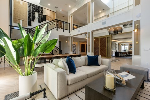 A living room with a couch, a table, and a potted plant.