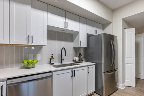 A kitchen with white cabinets and a stainless steel refrigerator.