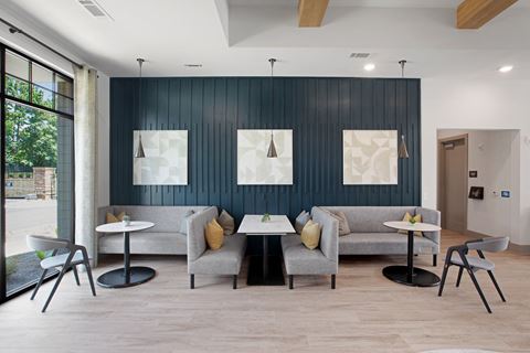 a seating area with couches and tables in front of a blue accent wall