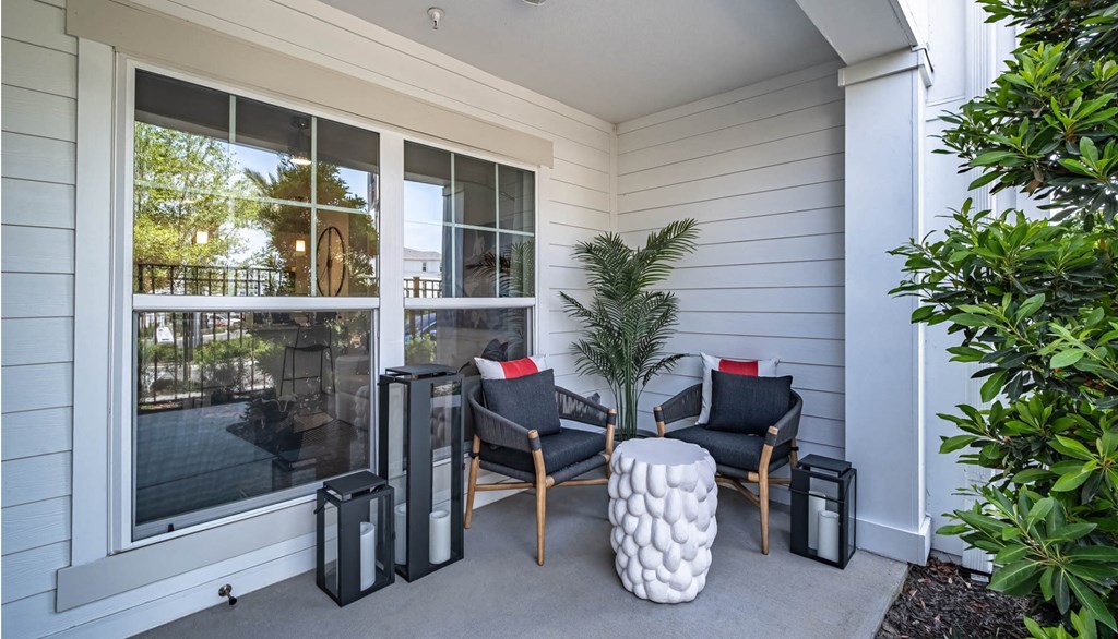 the front porch of a home with two chairs and a table