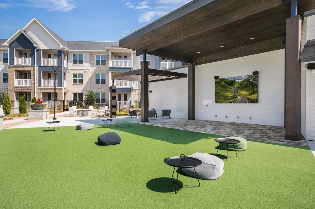 an outdoor lounge area with astroturf and stools