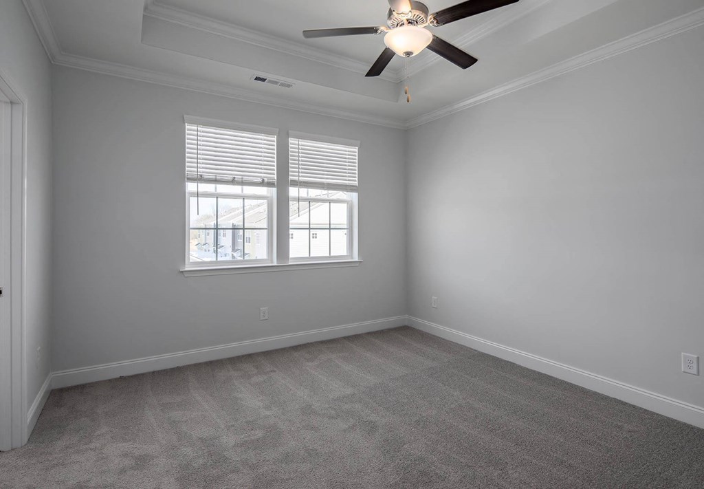 a bedroom with a ceiling fan and two windows