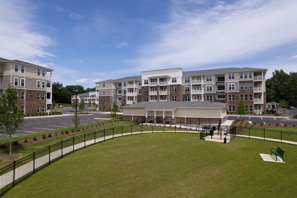 a building with a lawn in the foreground and a parking lot in the background